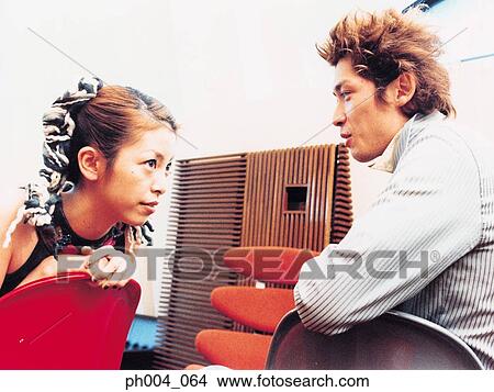 Picture - Young man and woman sitting across from each other, talking, close up. Fotosearch