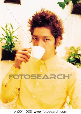 Stock Image - Young man drinking from cup, close-up. Fotosearch