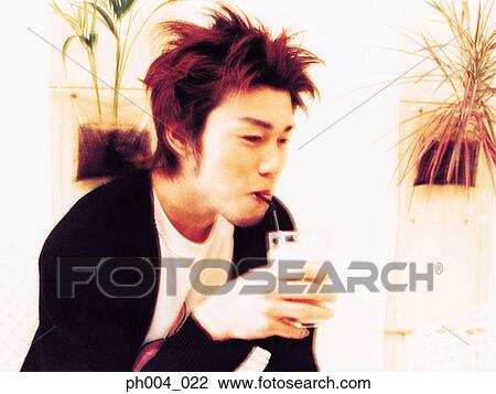 Stock Image - Young man having drink at a café, close up. Fotosearch