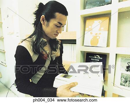 Picture - Young man reading book in book shop. Fotosearch