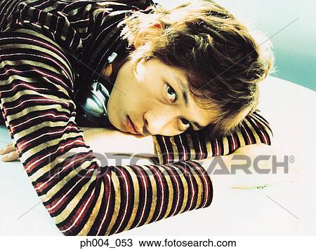 Stock Image - Young man resting head on table, portrait, close-up . Fotosearch