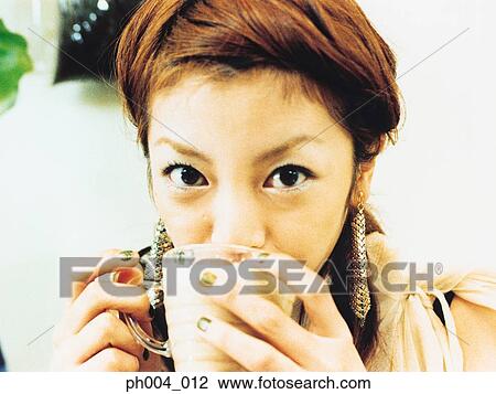 Stock Image - Young woman drinking cup of coffee, portrait, close-up . Fotosearch
