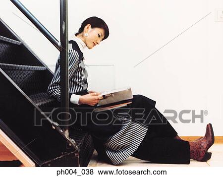 Stock Photo - Young woman reading on stairs. Fotosearch