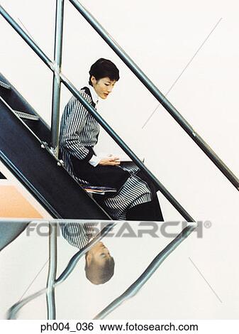 Young woman reading on stairs View Large Photo Image Stock Photograph - Young woman reading on stairs. Fotosearch