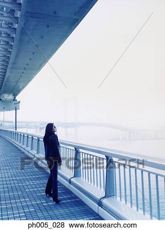 Woman standing by railing, under the bridge View Large Photo Image Stock Photo - Woman standing by railing, under the bridge. Fotosearch