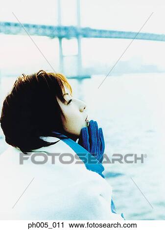 Stock Image - Young woman at waterfront, bridge in background. Fotosearch