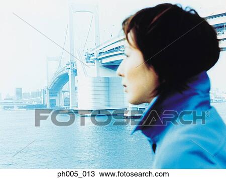 Young woman at waterfront, bridge in background View Large Photo Image Stock Image - Young woman at waterfront, bridge in background. Fotosearch