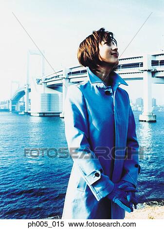 Stock Photography - Young woman at waterfront, bridge in background. Fotosearch