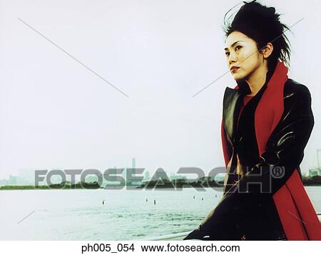 Young woman at waterfront, city in background View Large Photo Image Picture - Young woman at waterfront, city in background. Fotosearch