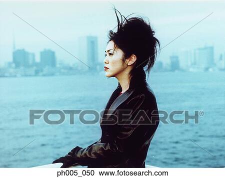 Young woman at waterfront, city in background View Large Photo Image Stock Image - Young woman at waterfront, city in background. Fotosearch