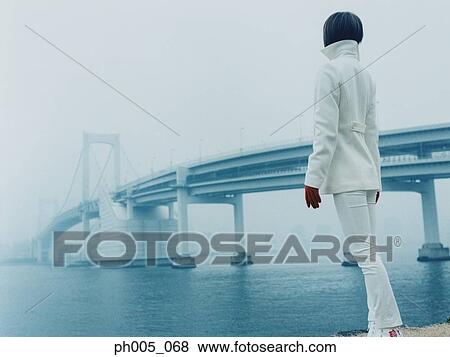 Young woman at waterfront, near bridge View Large Photo Image Stock Photo - Young woman at waterfront, near bridge. Fotosearch