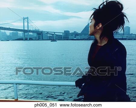 Young woman leaning against railing, city in background View Large Photo Image Stock Image - Young woman leaning against railing, city in background. Fotosearch