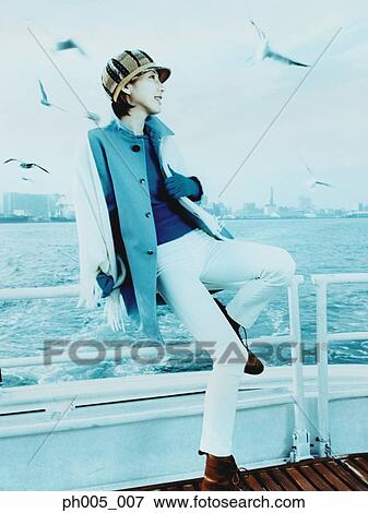 Young woman on ferry deck, Tokyo city in background, a flock of seagulls View Large Photo Image Stock Photo - Young woman on ferry deck, Tokyo city in background, a flock of seagulls. Fotosearch