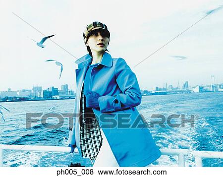 Stock Photo - Young woman on ferry deck, Tokyo city in background, a flock of seagulls. Fotosearch