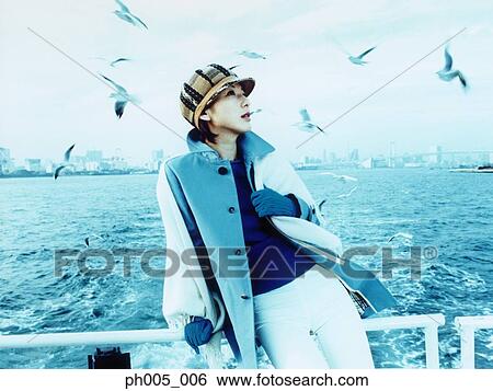 Young woman on ferry deck, Tokyo city in background, a flock of seagulls View Large Photo Image Stock Photograph - Young woman on ferry deck, Tokyo city in background, a flock of seagulls. Fotosearch