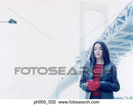 Stock Image - Young woman standing near bridge, close up, portrait. Fotosearch