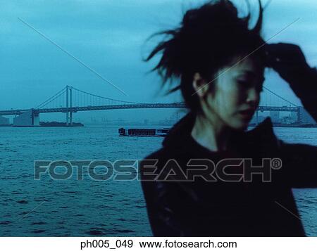 Stock Photo - Young woman with bridge in background, portrait. Fotosearch