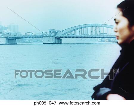 Young woman with city in background, close up View Large Photo Image Stock Photo - Young woman with city in background, close up. Fotosearch