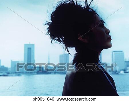 Young woman with city in background, close up View Large Photo Image Stock Photograph - Young woman with city in background, close up. Fotosearch