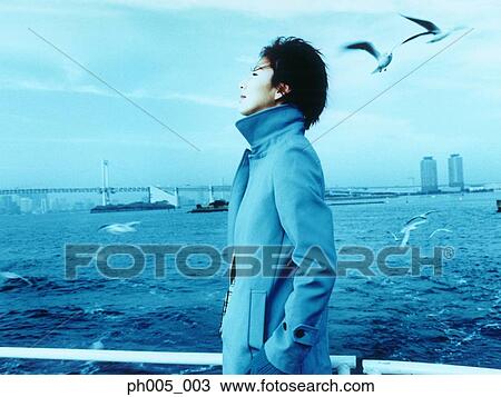 Stock Image - Young woman with Tokyo city in background, a flock of seagulls. Fotosearch