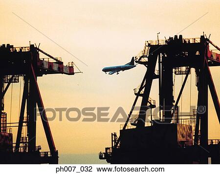 Passenger aircraft flying over port at sunset View Large Photo Image Stock Image - Passenger aircraft flying over port at sunset. Fotosearch