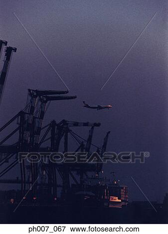 Passenger aircraft flying over port at night View Large Photo Image Stock Photo - Passenger aircraft flying over port at night. Fotosearch