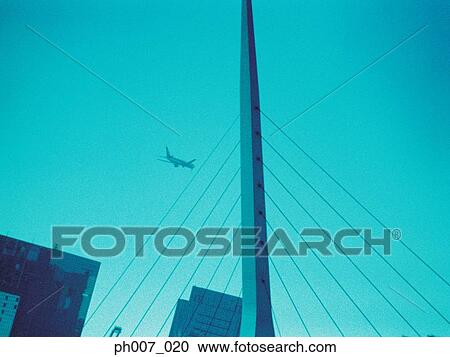 Passenger aircraft flying over skyscraper View Large Photo Image Stock Image - Passenger aircraft flying over skyscraper . Fotosearch
