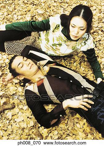 Couple lying on dried leaves covered ground View Large Photo Image Stock Image - Couple lying on dried leaves covered ground. Fotosearch