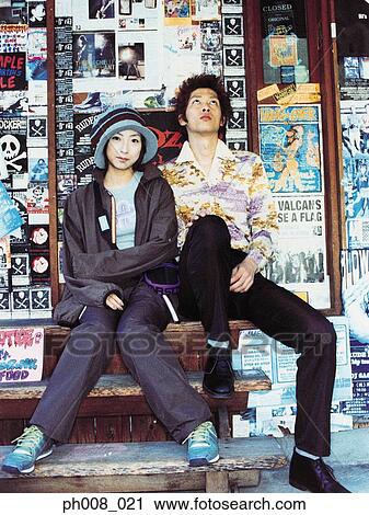 Stock Image - Couple sitting outside a shop. Fotosearch