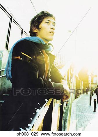 Man leaning on the staircase railing at sunset View Large Photo Image Stock Photo - Man leaning on the staircase railing at sunset. Fotosearch