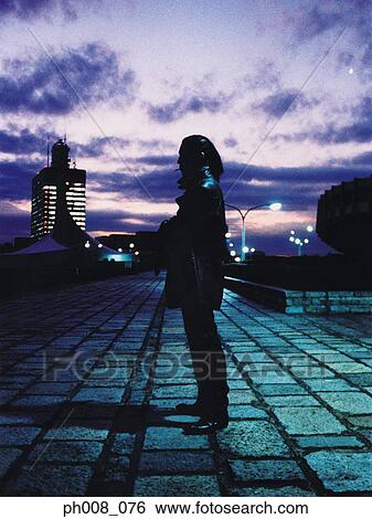 Stock Photograph - Silhouetted man standing in a park at sunset. Fotosearch