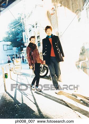 Stock Photo - Young couple walking and holding hands. Fotosearch