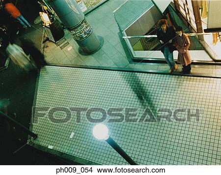 Couple standing at shopping center atrium, elevated view View Large Photo Image Picture - Couple standing at shopping center atrium, elevated view. Fotosearch