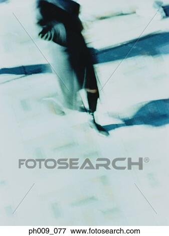 Stock Photo - Woman in trench coat walking (blurred motion). Fotosearch