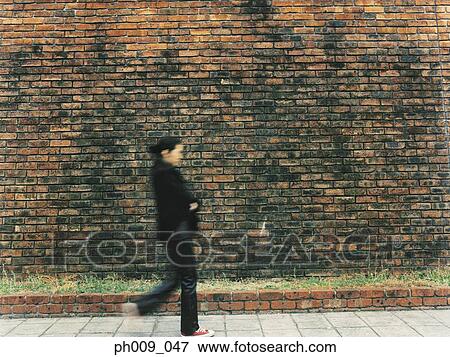Young woman walking, in front of Brick Wall View Large Photo Image Stock Photo - Young woman walking, in front of Brick Wall . Fotosearch