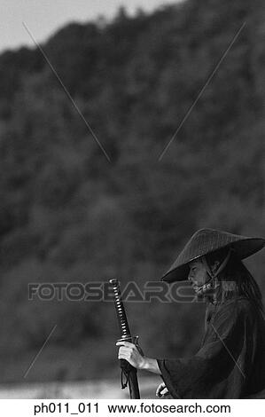 Samurai warrior holding a sword at the seaside View Large Photo Image Stock Image - Samurai warrior holding a sword at the seaside . Fotosearch