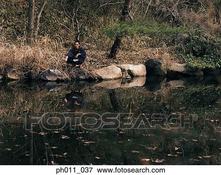 Stock Photo - Samurai warrior squatting at the edge of a pond. Fotosearch