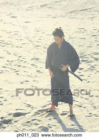 Samurai warrior standing at the beach holding a sword View Large Photo Image Stock Image - Samurai warrior standing at the beach holding a sword. Fotosearch