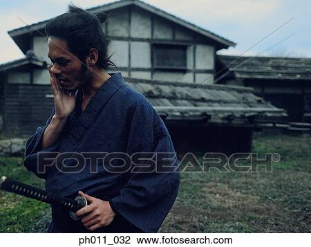 Samurai warrior walking in a village holding a sword View Large Photo Image Stock Image - Samurai warrior walking in a village holding a sword. Fotosearch