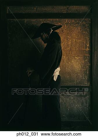 Stock Image - Samurai warrior standing in a room. Fotosearch