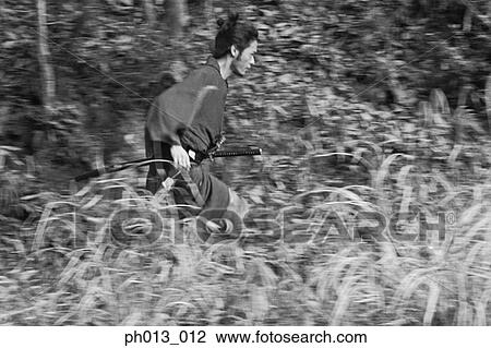 Stock Image - Samurai warrior running in an isolated land. Fotosearch