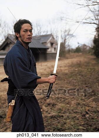 Stock Image - Samurai warrior standing with a sword in his hand. Fotosearch