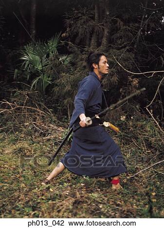 Stock Image - Samurai warrior walking with a sword in his hand. Fotosearch