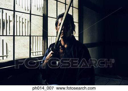 Samurai warrior holding a sword View Large Photo Image Stock Photo - Samurai warrior holding a sword. Fotosearch