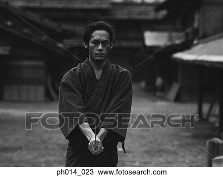 Stock Image - Samurai warrior standing with a sword in his hand. Fotosearch