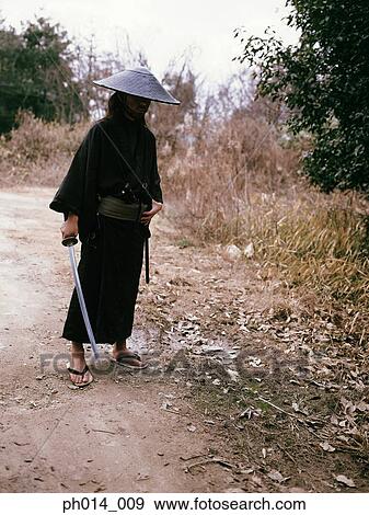 Samurai warrior standing with a sword in his hand View Large Photo Image Stock Photo - Samurai warrior standing with a sword in his hand. Fotosearch