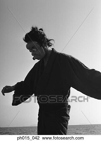 Stock Image - Portrait of a Japanese man in traditional costume wearing a mask. Fotosearch