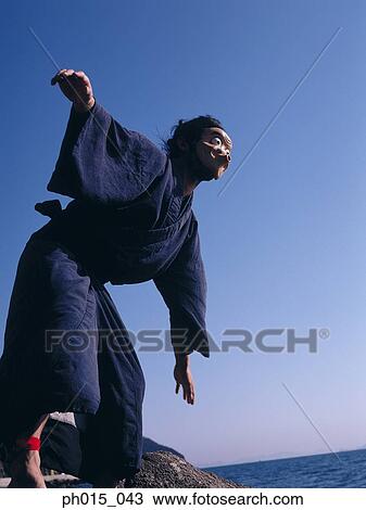 Stock Image - Portrait of a Japanese man in traditional costume wearing a mask. Fotosearch