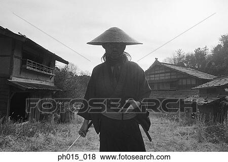 Samurai warrior standing, holding a sword View Large Photo Image Stock Photo - Samurai warrior standing, holding a sword. Fotosearch