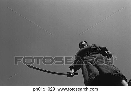 Samurai warrior standing, holding a sword View Large Photo Image Stock Photo - Samurai warrior standing, holding a sword. Fotosearch
